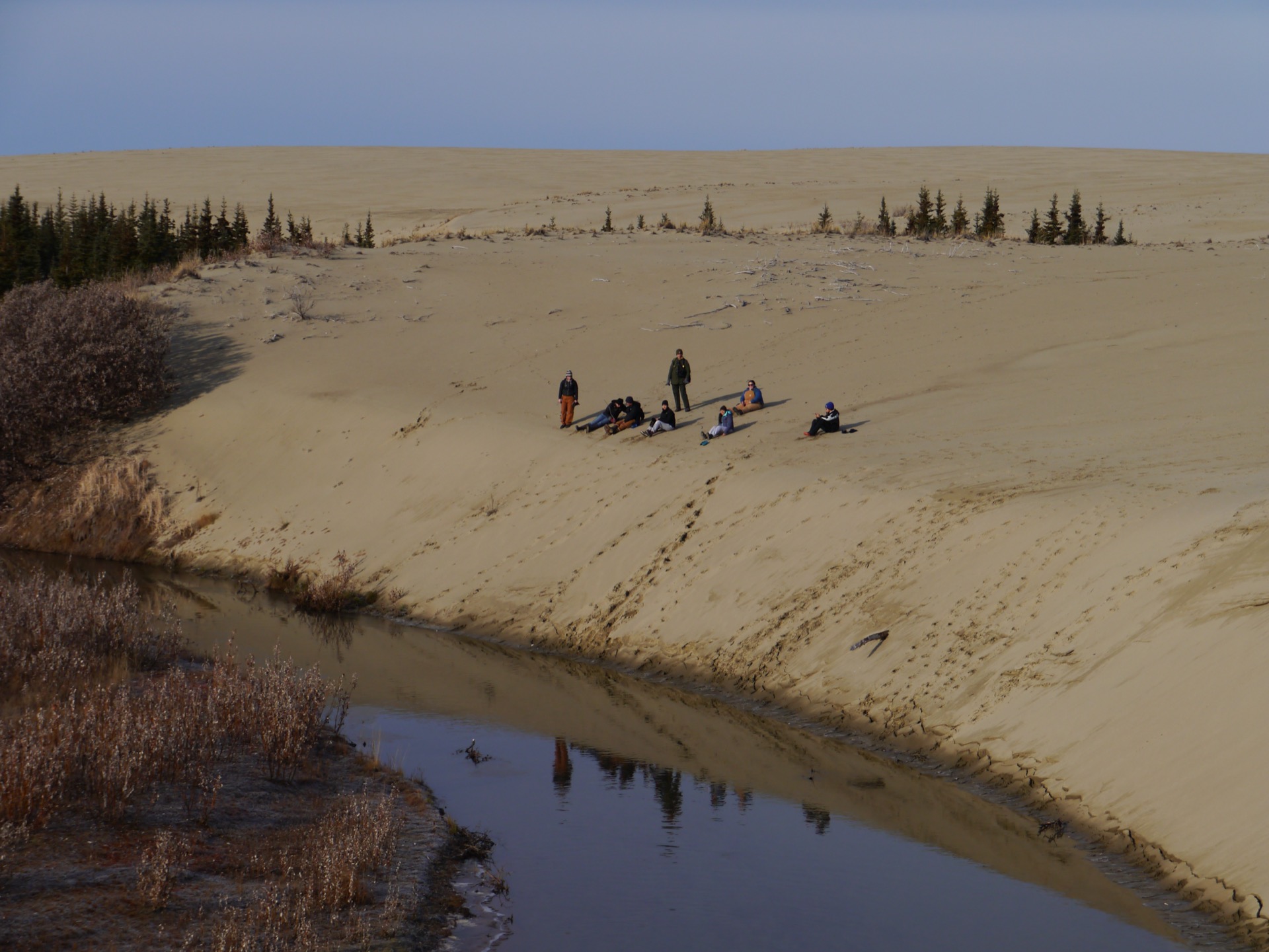 A hiker resting on the Great Kobuk Sand Dunes, an Arctic dune field in Kobuk Valley National Park
