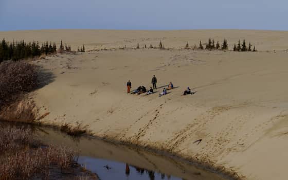 A hiker resting on the Great Kobuk Sand Dunes, an Arctic dune field in Kobuk Valley National Park